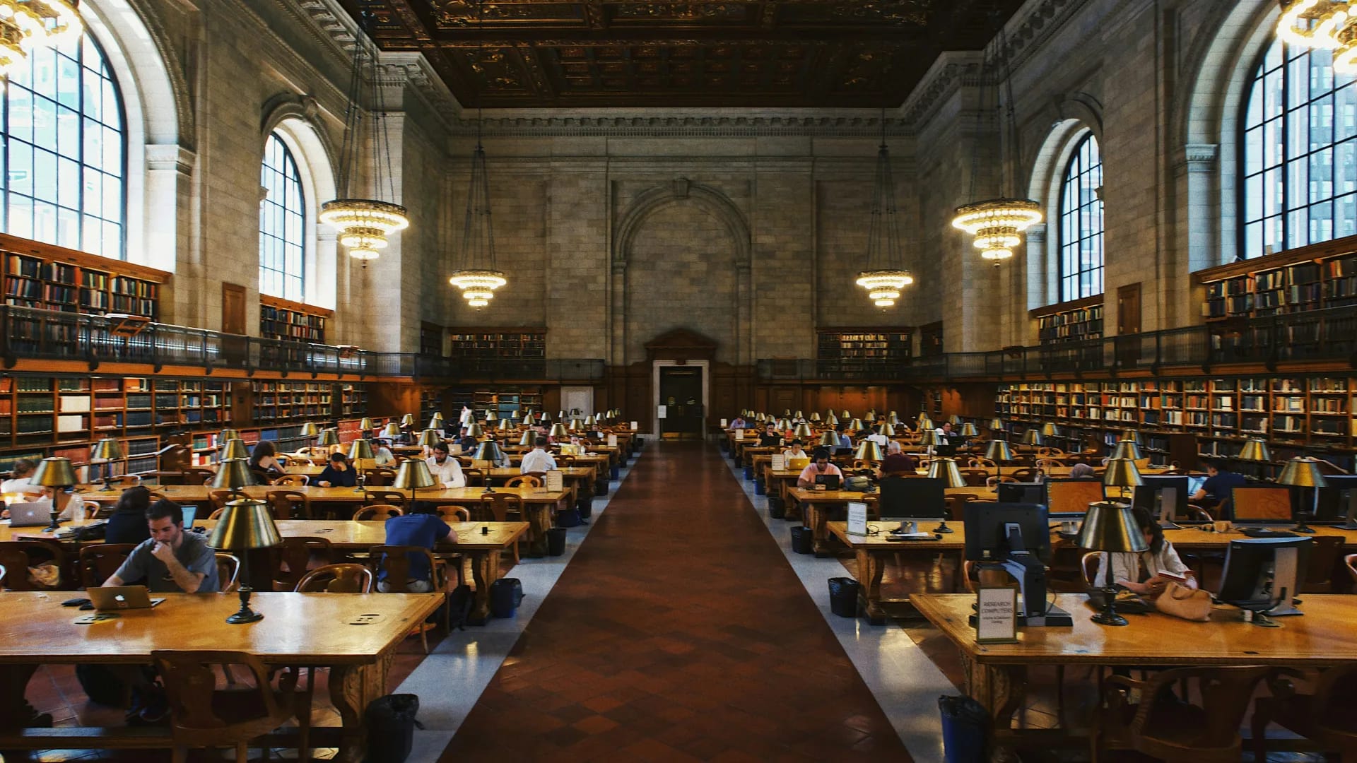 Lesesaal einer Universitätsbibliothek mit Studierenden an langen Arbeitstischen