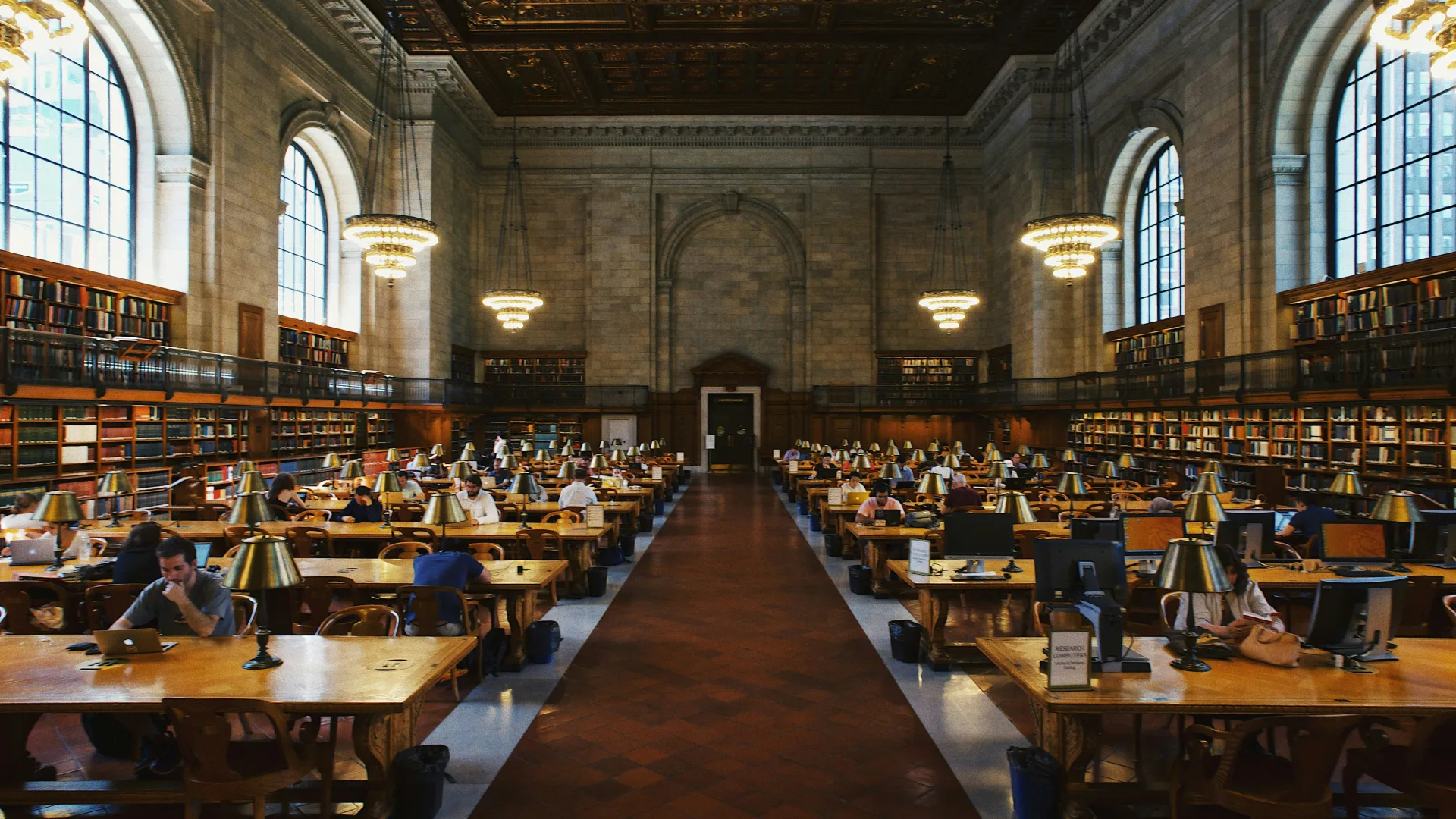 Lesesaal einer Universitätsbibliothek mit Studierenden an langen Arbeitstischen