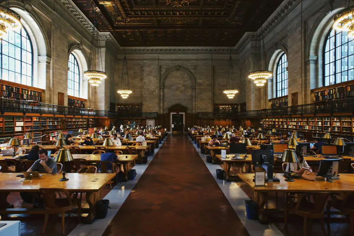 Historischer Bibliotheks-Lesesaal, Studierende arbeiten an langen Holztischen unter Messinglampen